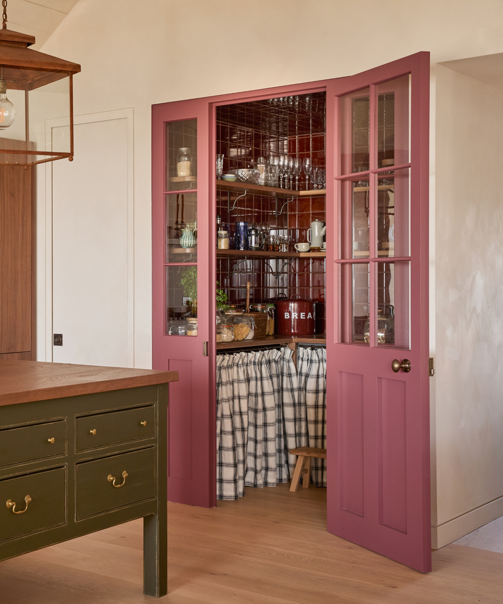 A walk-in pantry with pink doors with upper glazing