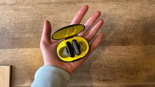 Logitech G Fits earbuds in black and yellow case sitting in a hand