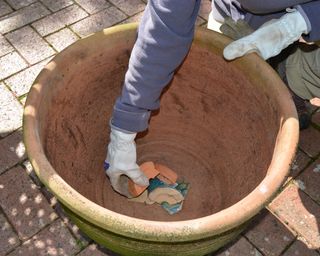 Lining a container with crocks for drainage before planting summer bedding