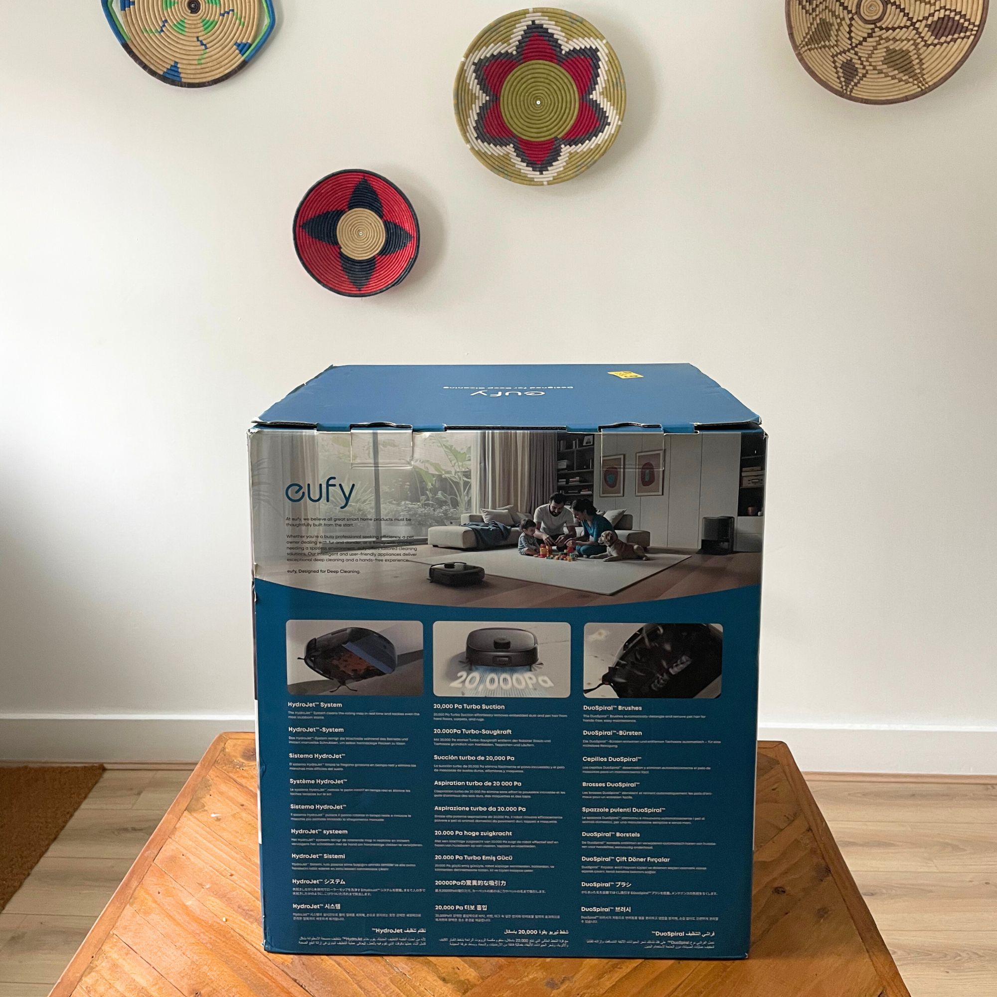 Eufy Robot Vacuum Omni E25 box sitting on a wooden table with a white wall behind it