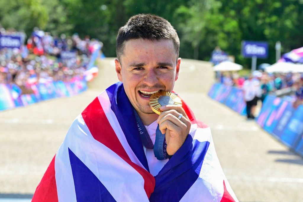 Britain's Thomas Pidcock poses for photographs as he celebrates his gold medal victory after winning the men's cross-country mountain biking event during the Paris 2024 Olympic Games in Elancourt Hill venue in Elancourt, on July 29, 2024. (Photo by John MACDOUGALL / AFP)