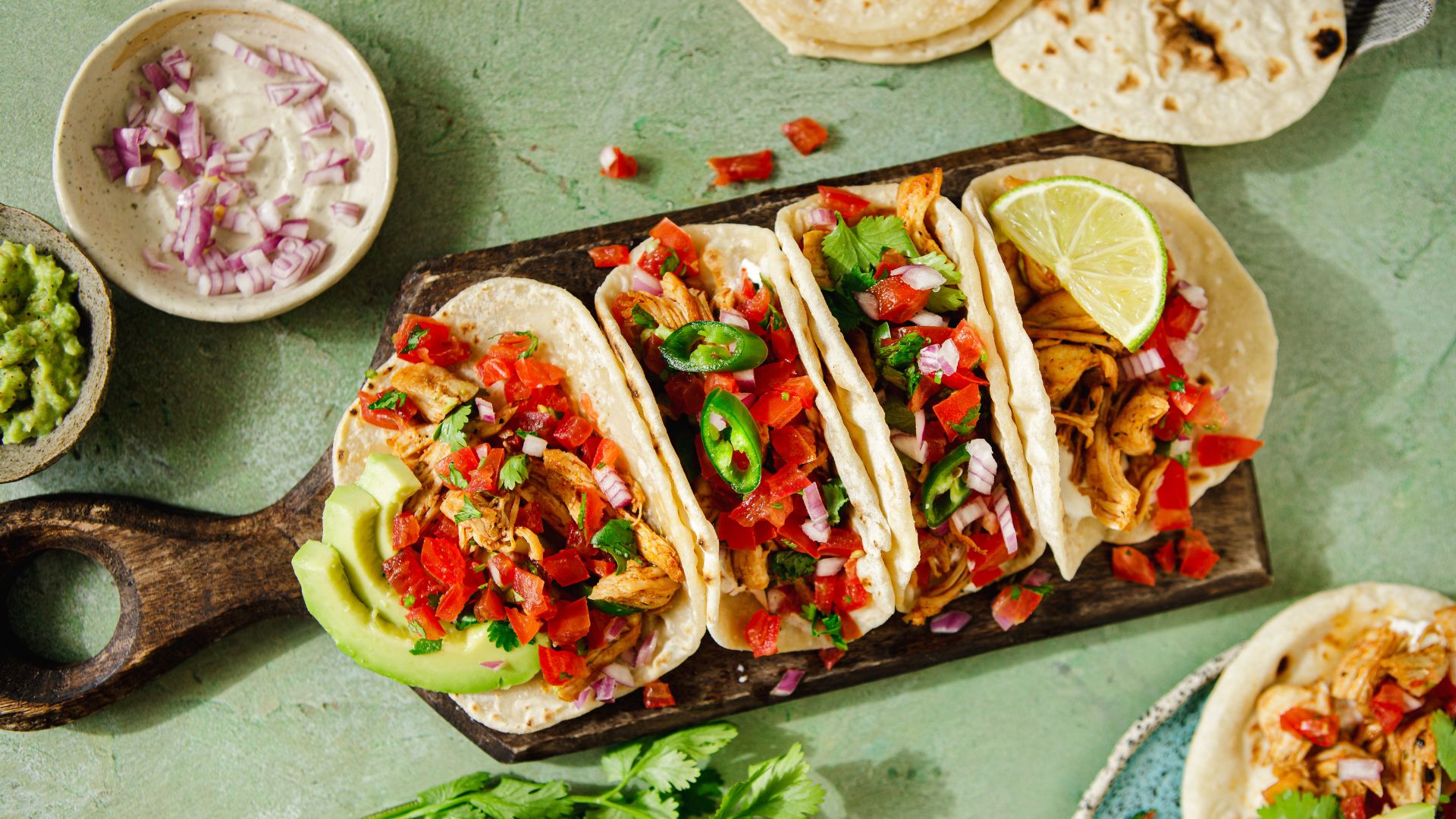 an image of four tacos lines up on a wooden board