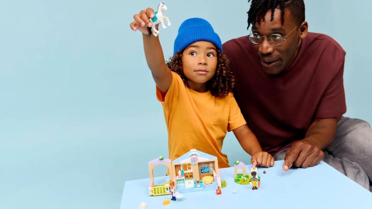 A child plays with a Lego vet set, with an adult looking on