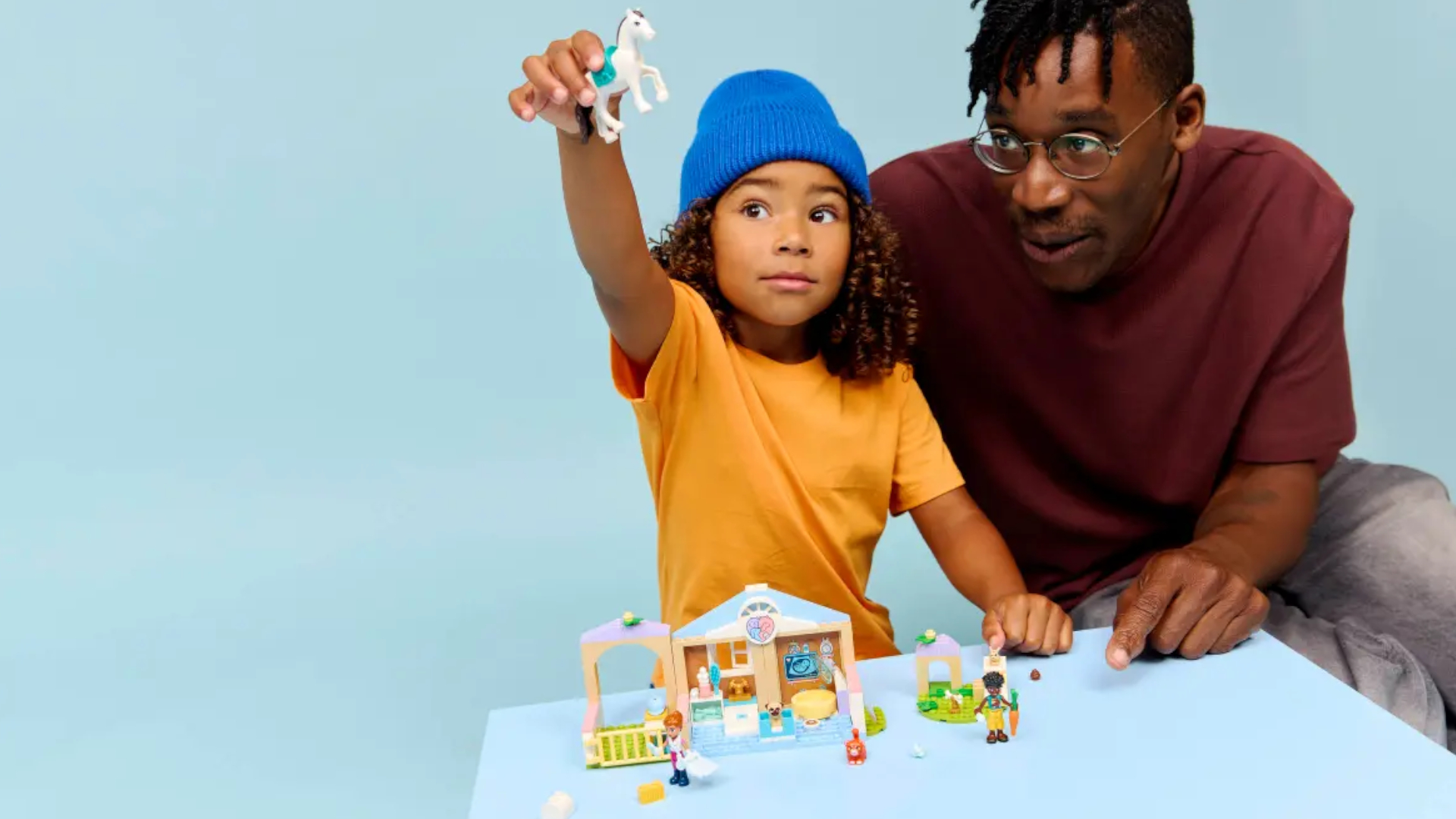A child plays with a Lego vet set, with an adult looking on 