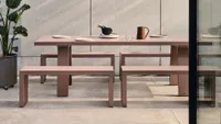 A contemporary metal garden table and outdoor bench seats in a soft pink colour
