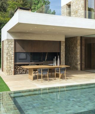 A covered outdoor dining and living area with a small tiled pool in the foreground