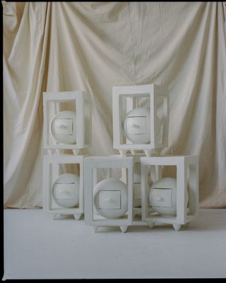white bold vases shown on a gridded shelving unit, by simone bodmer turner