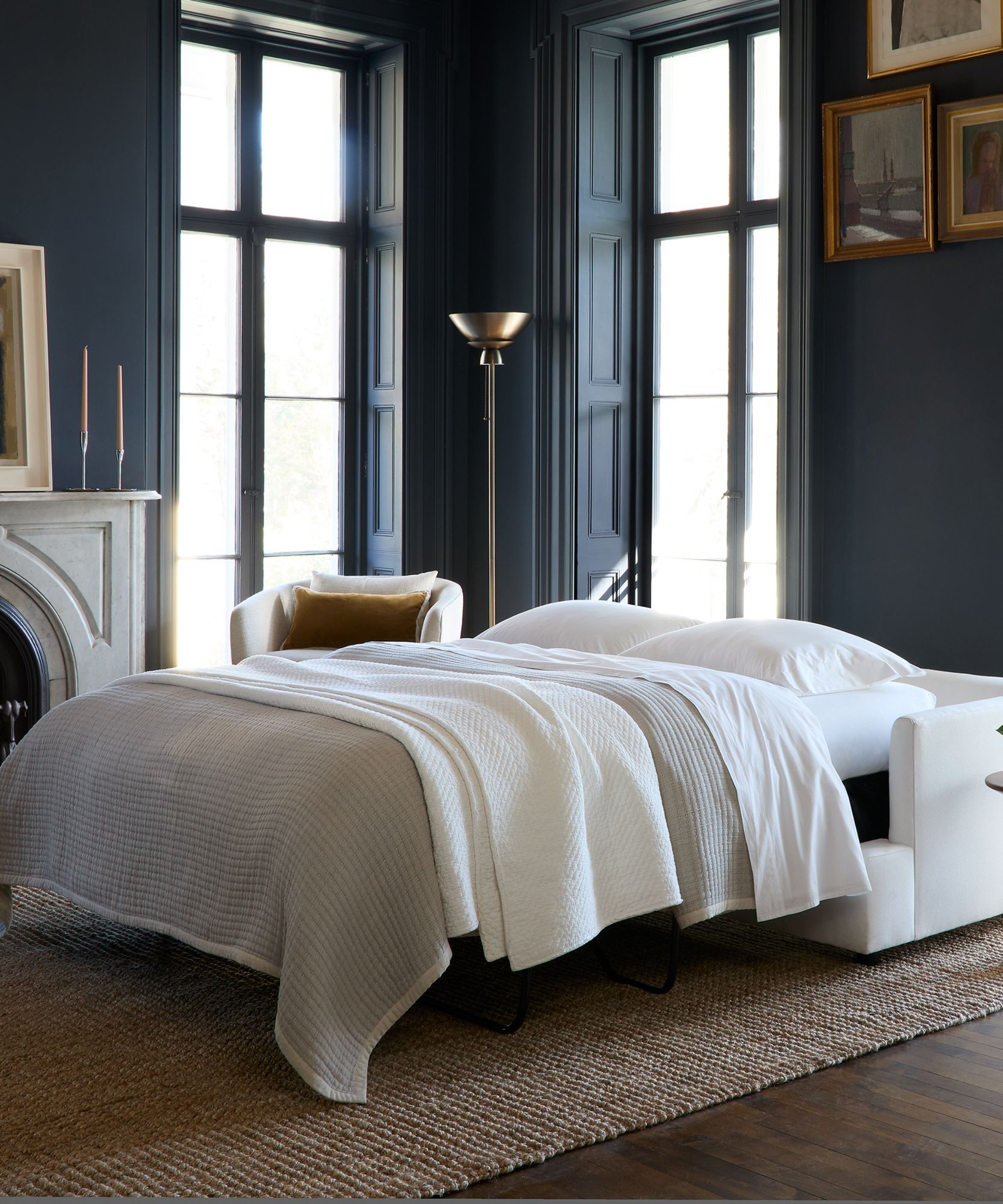 Opulent, sundrenched navy living room featuring a cream sleeper sofa styled with neutral bedding