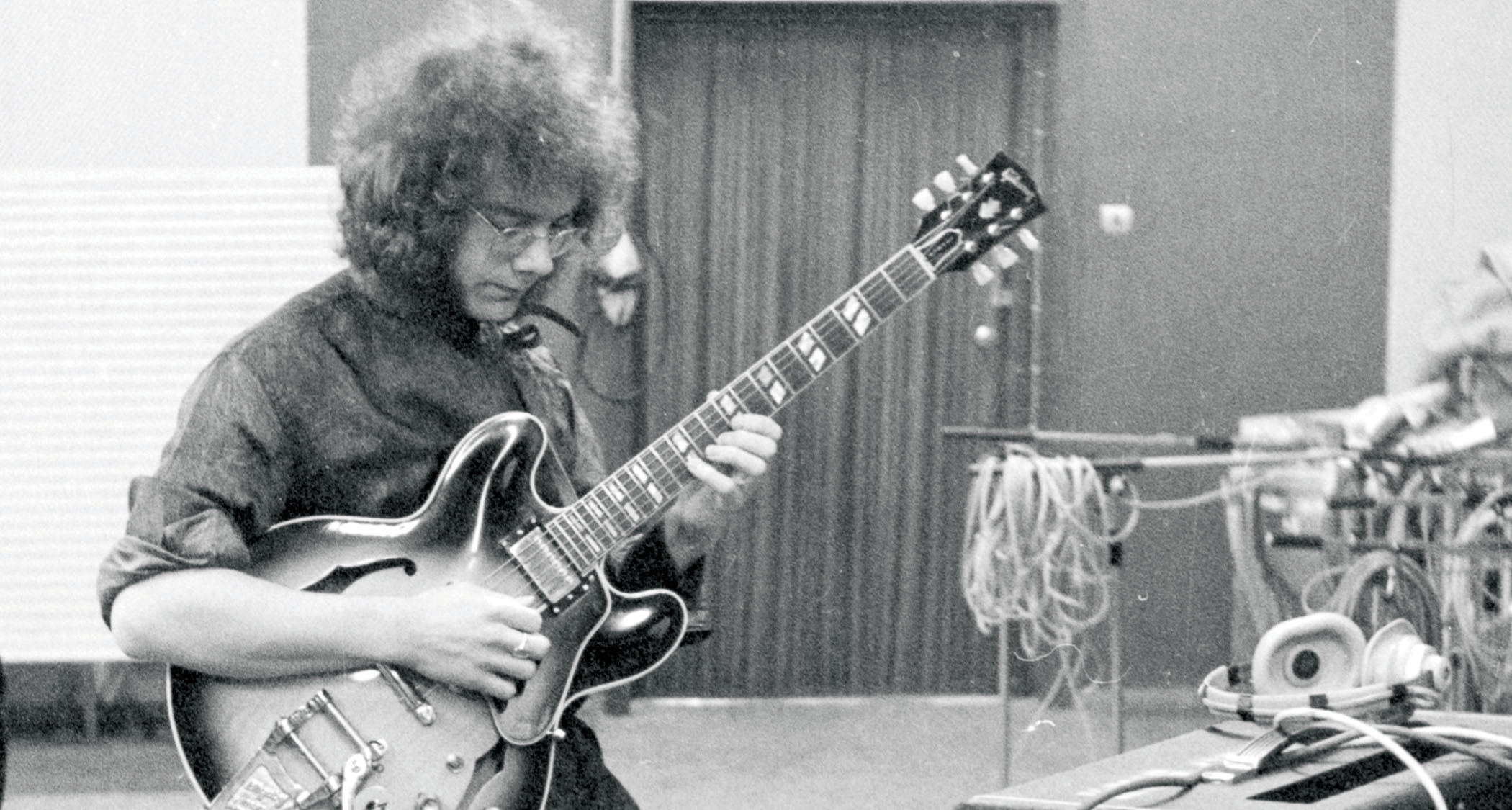 A black-and-white image of Robert Fripp playing his ES-345.