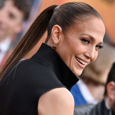 Jennifer Lopez looks over her shoulder wearing a black dress with her hair in a ponytail 