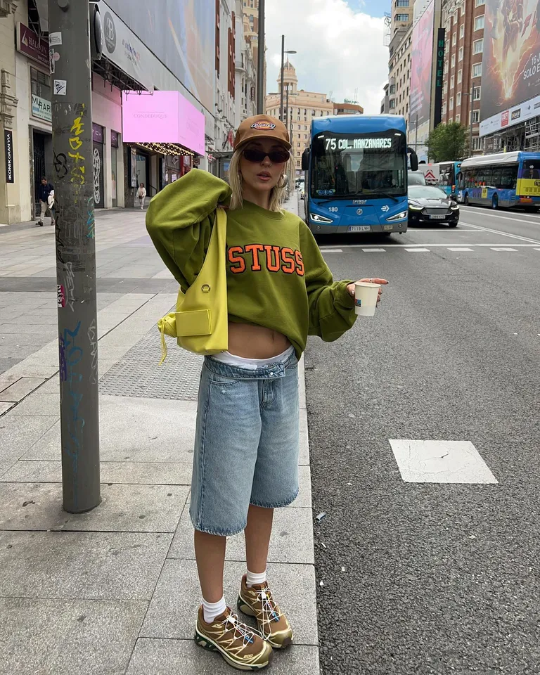 Woman in jorts, sneakers, and sweater