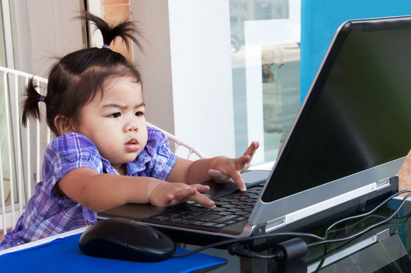 a baby types away on a laptop computer