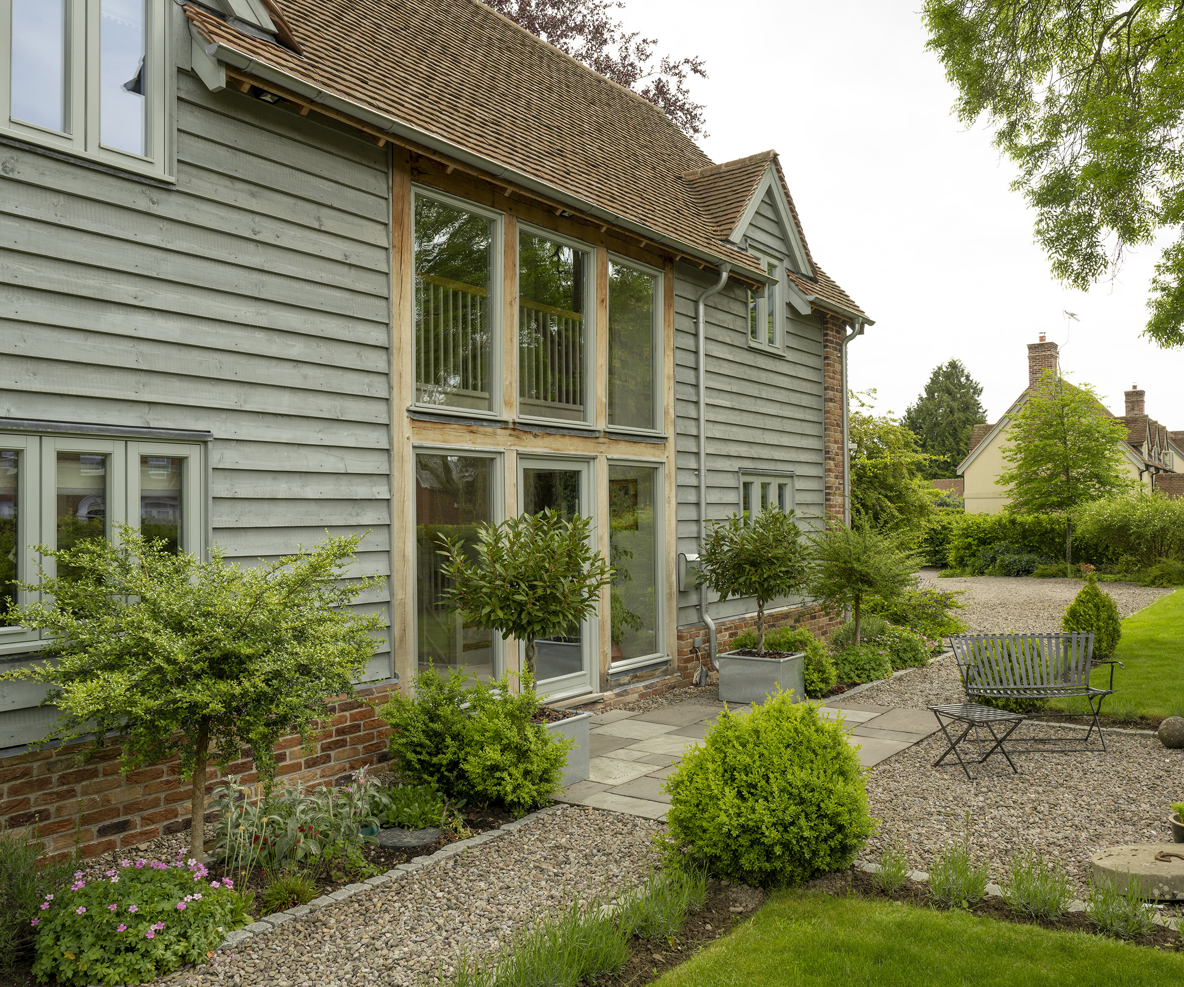 Exterior of a two storey oak frame house with brick and wood cladding with stone and gravel patio