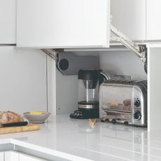 A white kitchen with hidden storage for a kettle and toaster