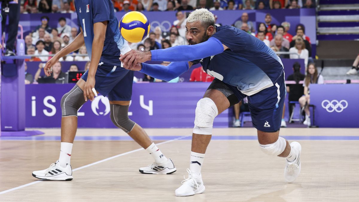 Earvin Ngapeth, in blue shirt and shorts, digs the ball out of trouble for France in the men&#039;s volleyball at the 2024 Paris Olympic Games.