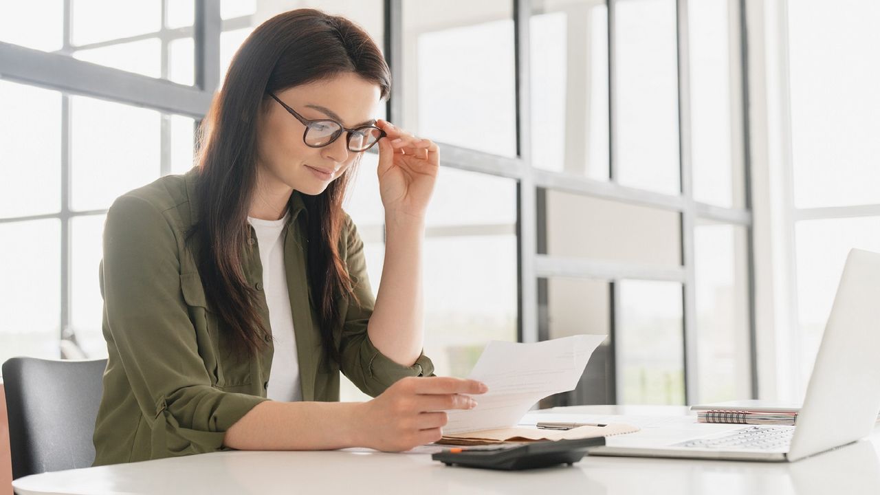 A woman in her office looks at bills.