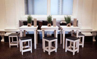 Small wooden white tables and stool seating area
