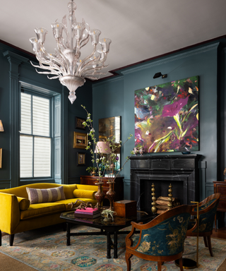 Eclectic living room in denim blue with mustard couch and statement light pendant