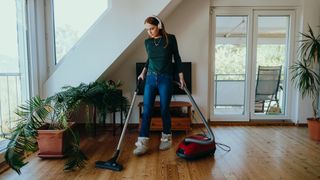Woman wearing headphones showing how to clean hardwood floors with a vacuum.