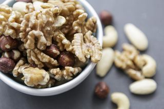 A bowl full of pecan nuts on a grey worksurface