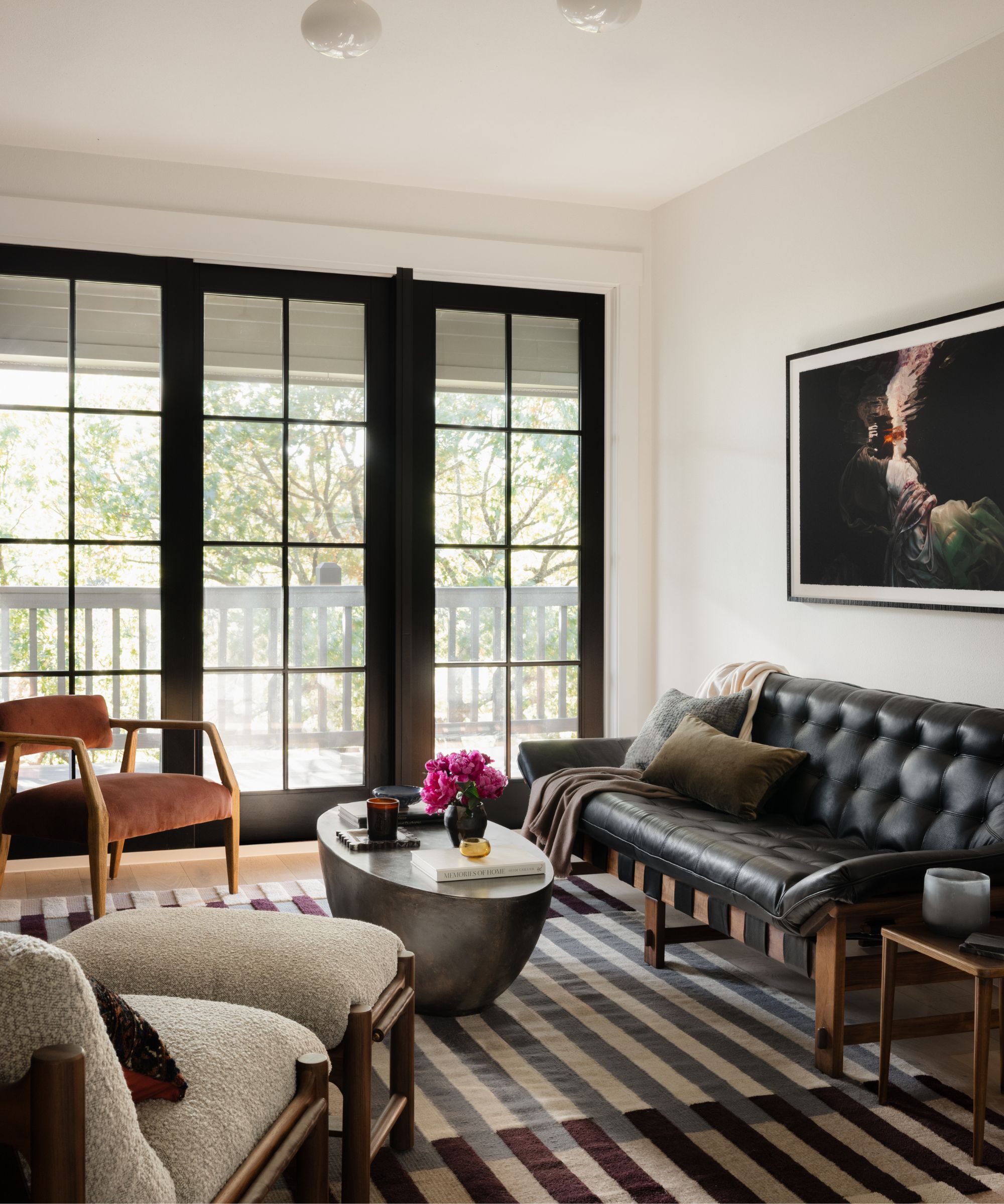 a neutral upstairs loft sitting room with patio doors and vintage mid century furniture arranged on a striped rug