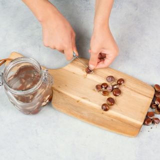 Person cutting conkers on a wooden chopping board