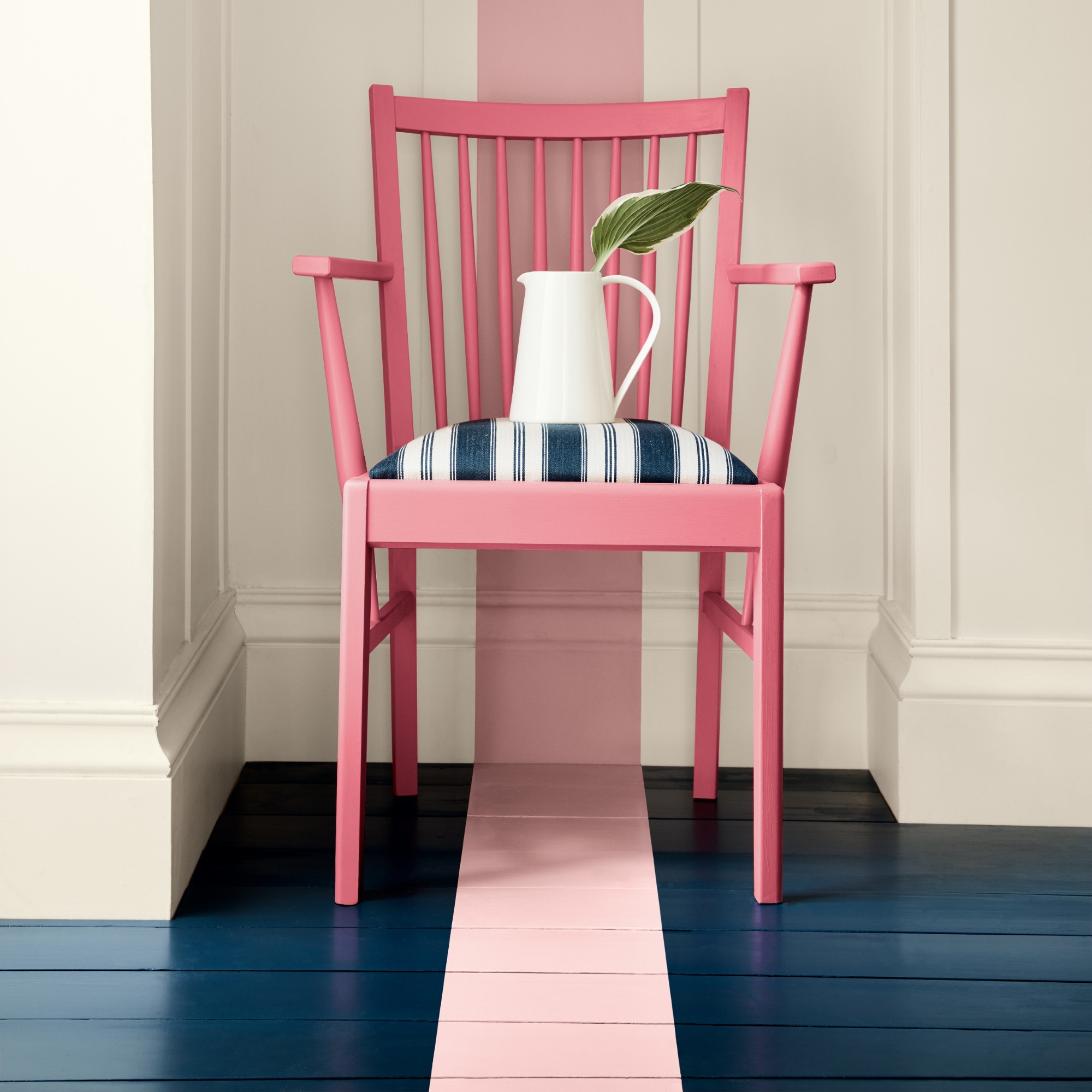A painted wooden floor in navy blue with a pink stripe that continues across the floor up to the off-white wall
