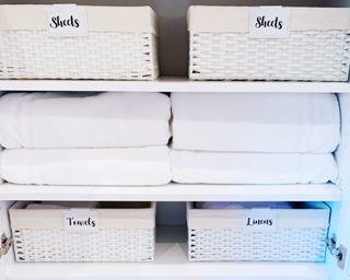 A linen closet organized with storage baskets and folded towels