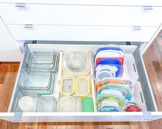 A white kitchen drawer with a set of colorful organized food storage containers