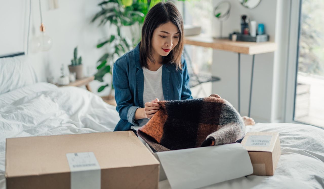 Beautiful smiling young Asian woman unpacking delivery box. Online hopping at home is efficient and convenience. Home Delivery service.