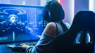 gamer sits in chair with headset in front of PC monitor
