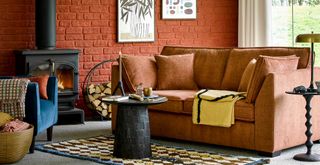 Rust coloured living room with terractorra painted brick wall and rust coloured sofa to support a key interior design trend 2023
