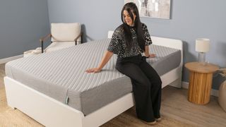 A woman sits on the edge of the Siena Memory Foam Mattress in a bedroom