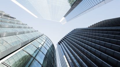 Looking up amid a cluster of skyscrapers rising into a blue sky.