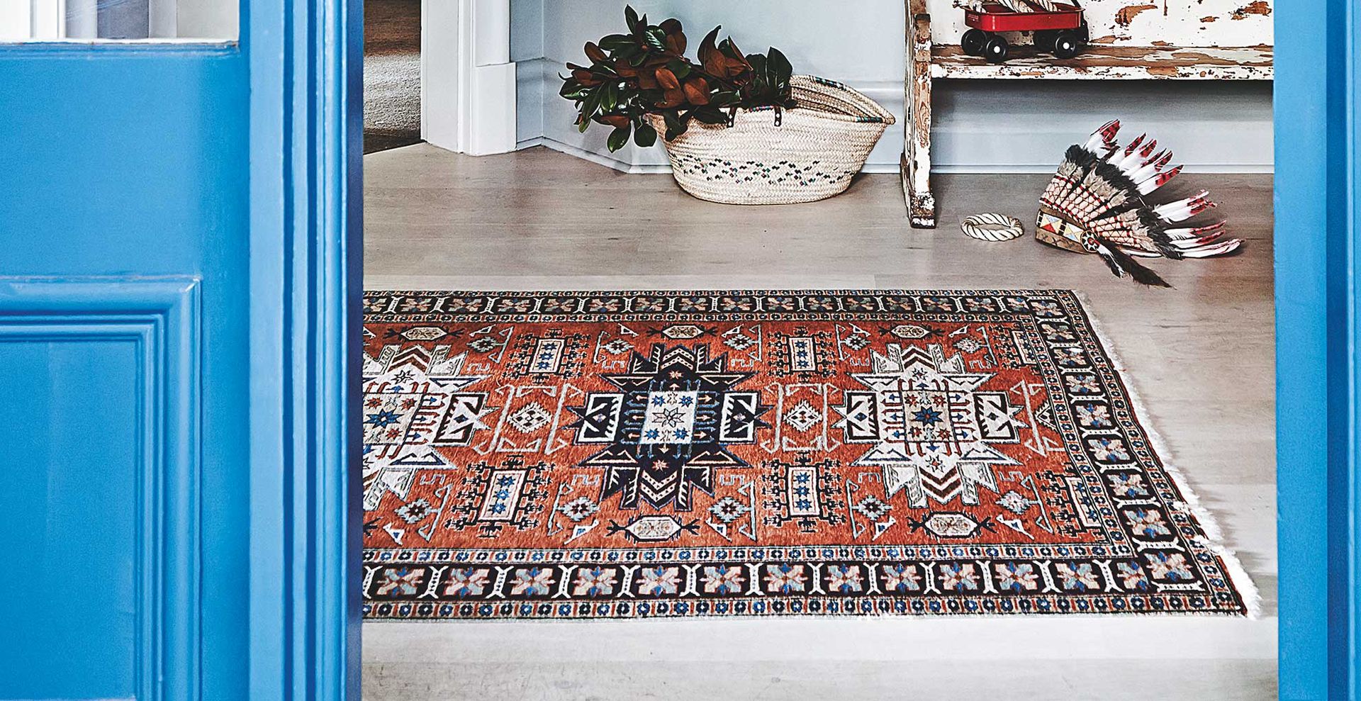 Hallway with blue front door leading to a traditional rug on a tiled floor to support a guide for how to clean a rug at home