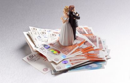 Model bride and groom back to back on top of a pile of money notes
