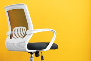 Part of ergonomic desk chair in front of yellow background