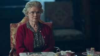 Queen Elizabeth II sits in a dark room in The Crown season 6