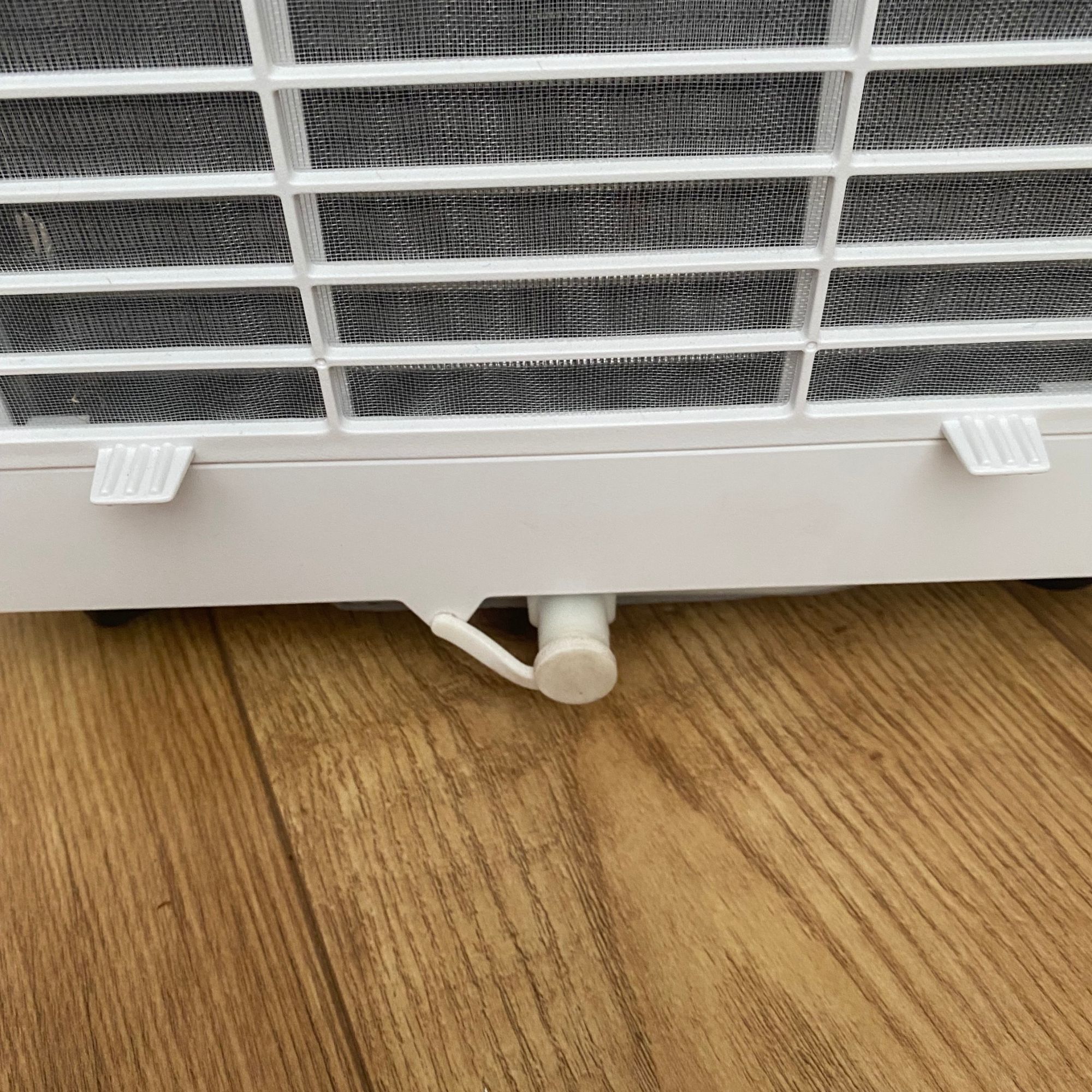 Drainage outlet of the Devola DVAC09CW portable air conditioner, standing on a wood-look floor