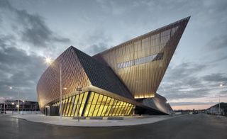 New convention centre in Mons, lit up at dusk by internal lighting together with street lights surrounding the building