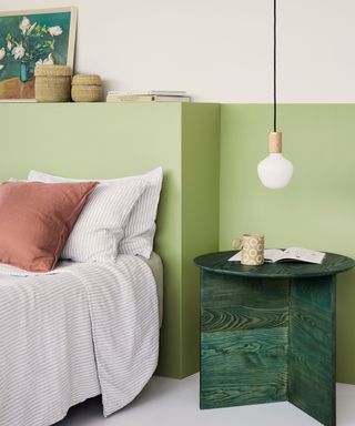 bedroom with lower half of wall painted green and pendant light hanging next to bed with white glass shade