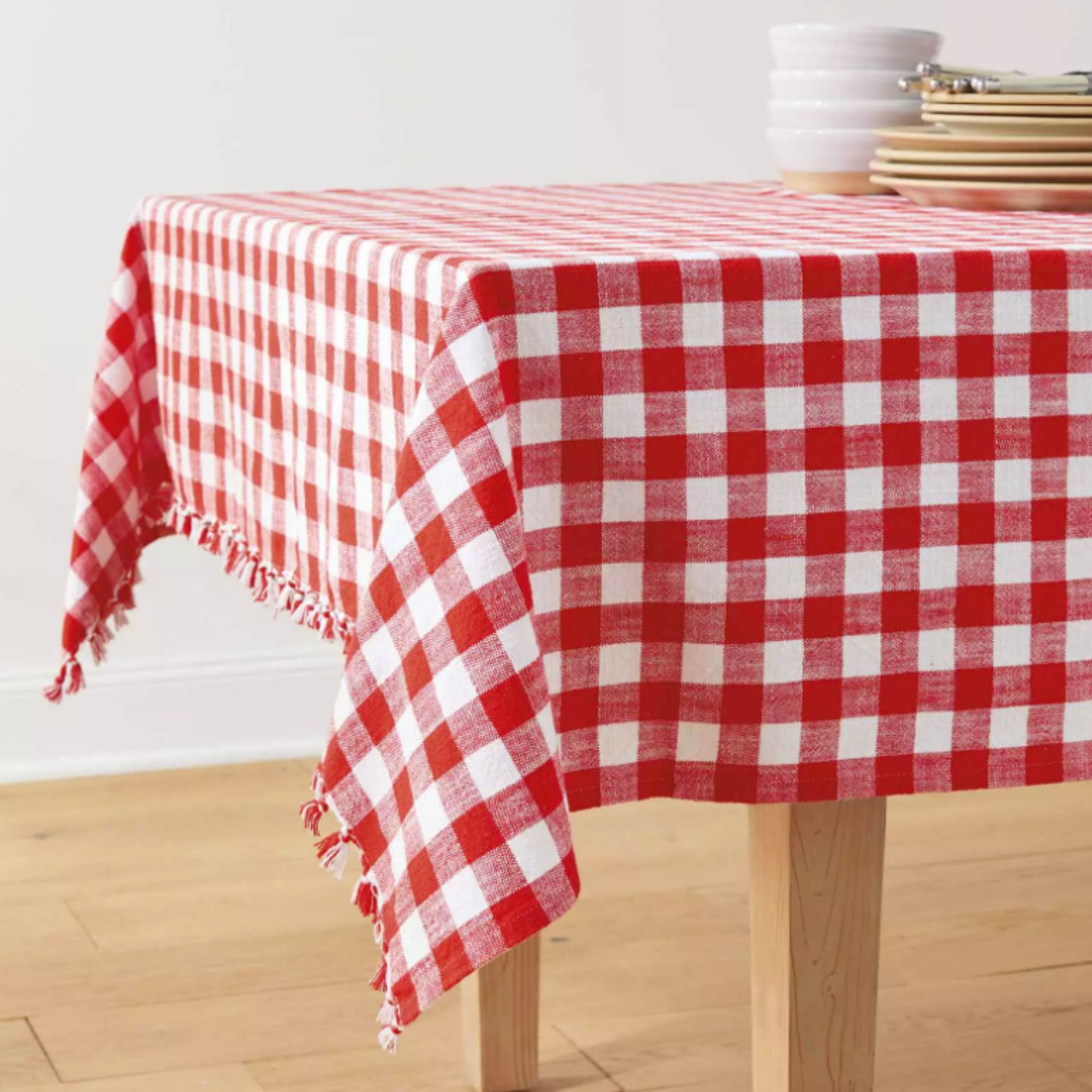 Red and white gingham tablecloth on a table with some plates and bowls on top