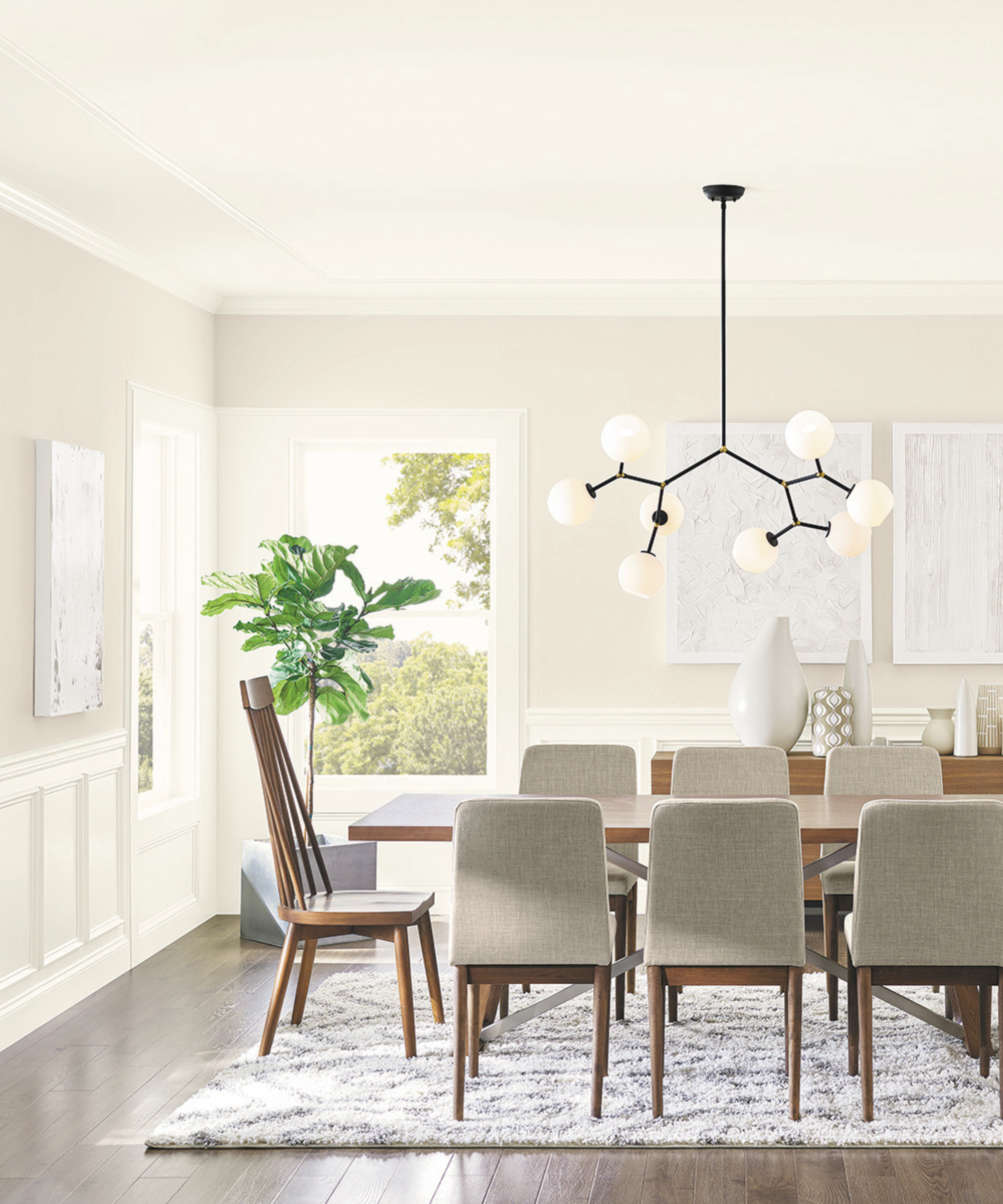A white, bright dining room with a wooden dining table and a black, modern light fixture