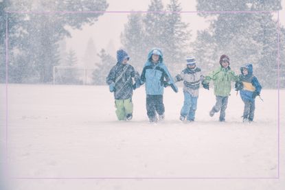 Five children holding hands and walking through the snow