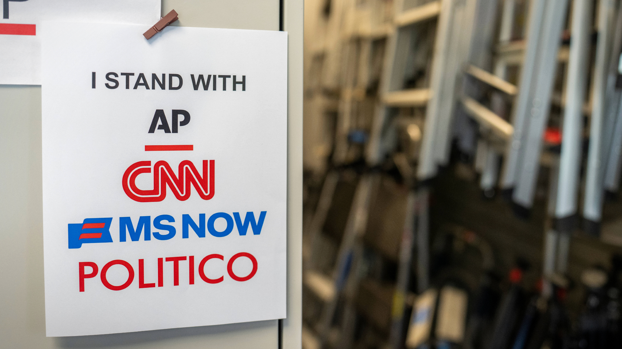 A sign in support of AP, CNN, MS NOW, and Politico near the James S. Brady Press Briefing Room of the White House.
