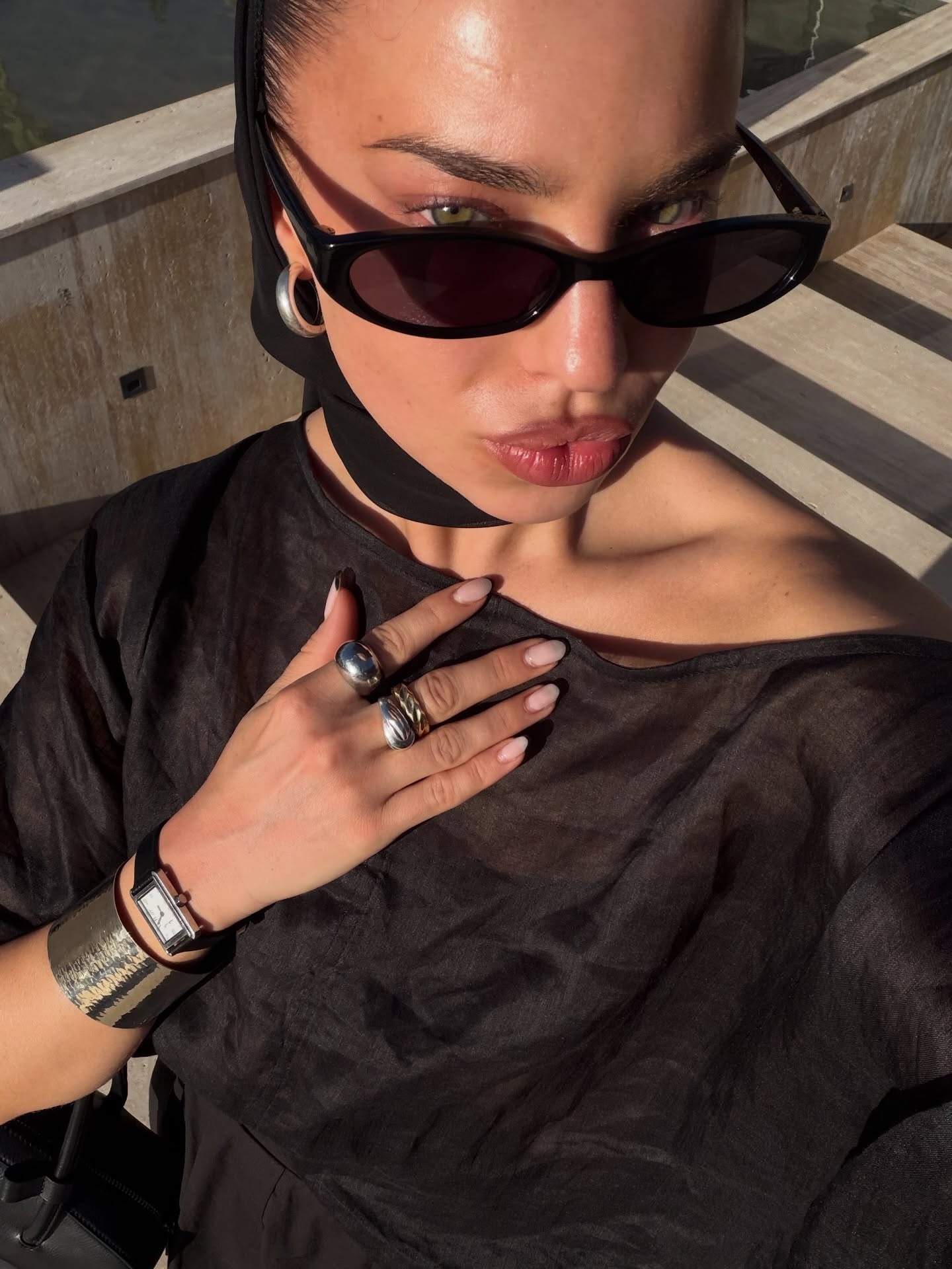 Hetty Appletonmiles wears black oval sunglasses and an all black outfit with silver jewellery