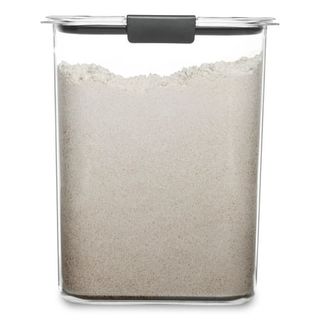 a tall glass food storage container with a locking lid. filled with flour