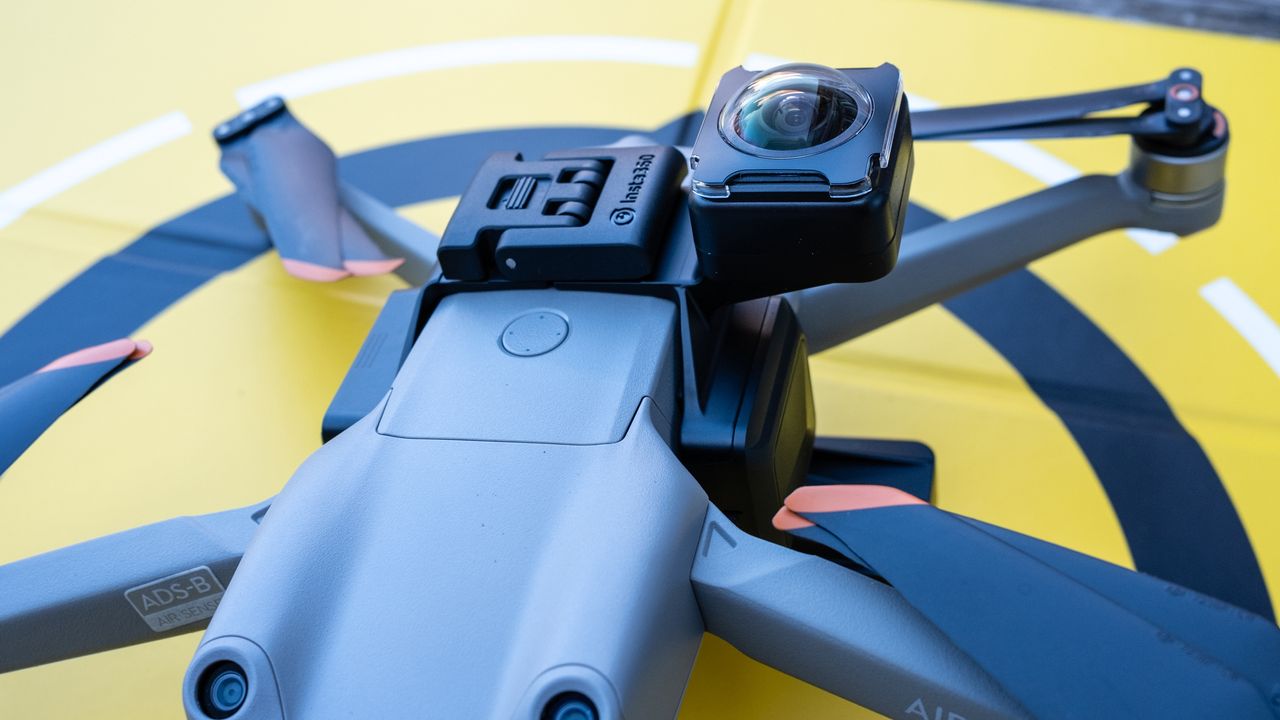 A DJI drone on a wooden table connected to the Insta360 Sphere 360 camera
