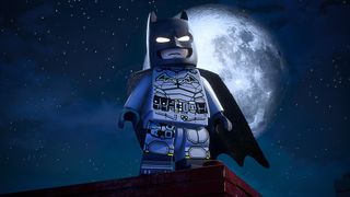 A screenshot from Lego Batman, showing the titular Lego Batman on top of a building, with the moon behind him