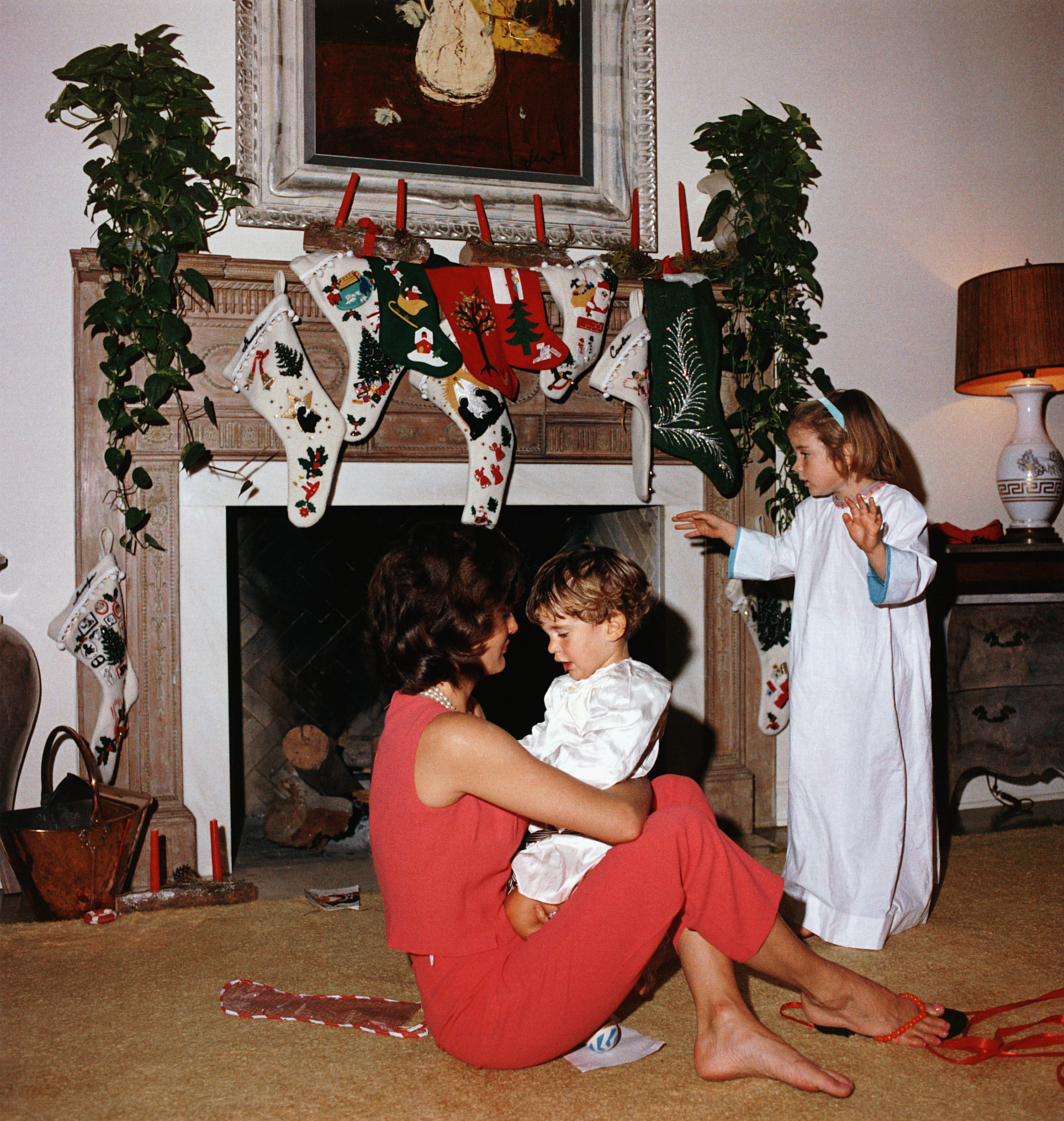 Jacqueline Kennedy with the children on Christmas morning. She sits on the floor, holding John on her lap, and Caroline stands nearby in her nightgown. Several stockings hang from the mantle. (Photo by &amp;copy; CORBIS/Corbis via Getty Images)